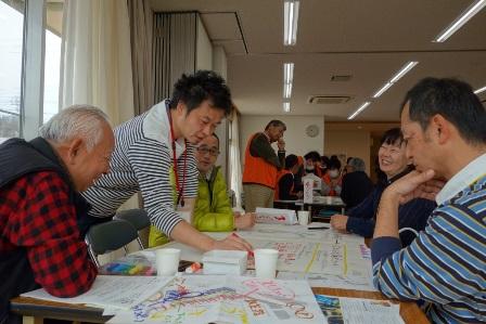 男性が資料にペンで書き込みながらその様子を他の参加者が見ている写真