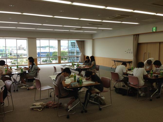 参加者がグループに分かれて席について、レポートをまとめたり、話し合いをしたりしている様子の写真