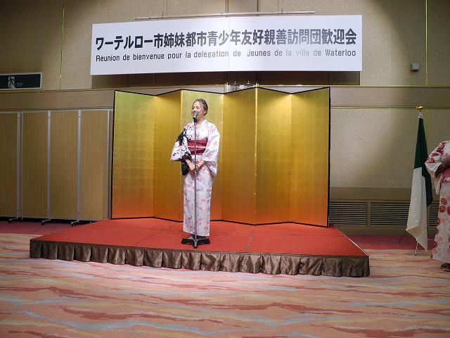金屏風の前に立って挨拶をしている浴衣姿のワーテルロー市訪問団の女子学生の写真