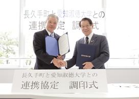長久手町と愛知淑徳大学との連携協定 調印式にて、調印した文書をこちらに向けながら握手をする小林素文学長と加藤梅雄町長の写真