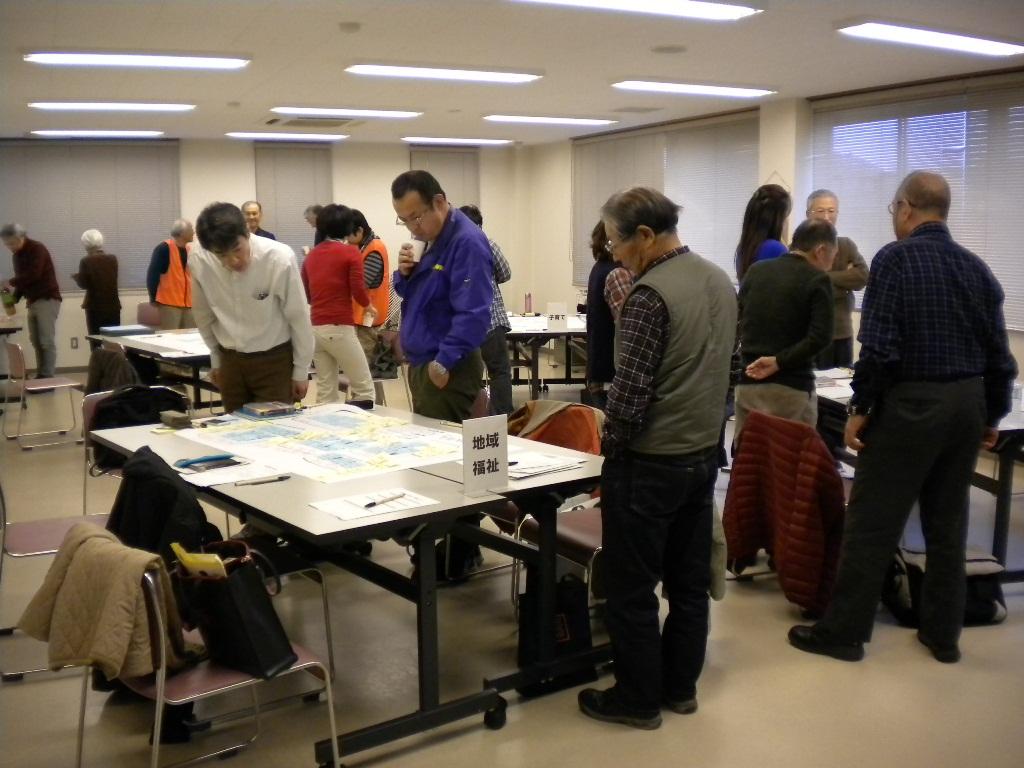 机に置かれた資料に目を配っている方々の写真