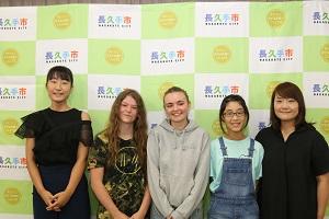長い髪の女の子とグレーのパーカーを着た女の子、ホストファミリーの親子(お母さんと姉妹)が写っている写真