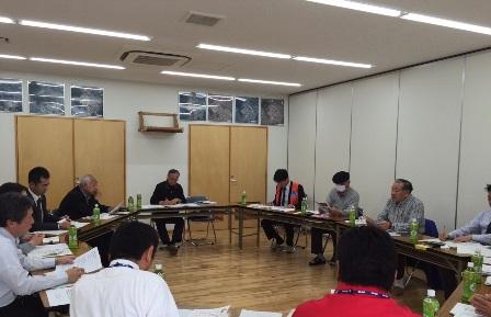 お互いの顔が見えるように設置されている長机に関係者の皆さんが席についており、話し合いが行われている様子の写真