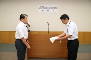 演壇の前に向かい合って立っている町長と団長の写真