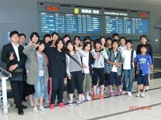 空港の掲示板の前で撮影した生徒たちの集合写真
