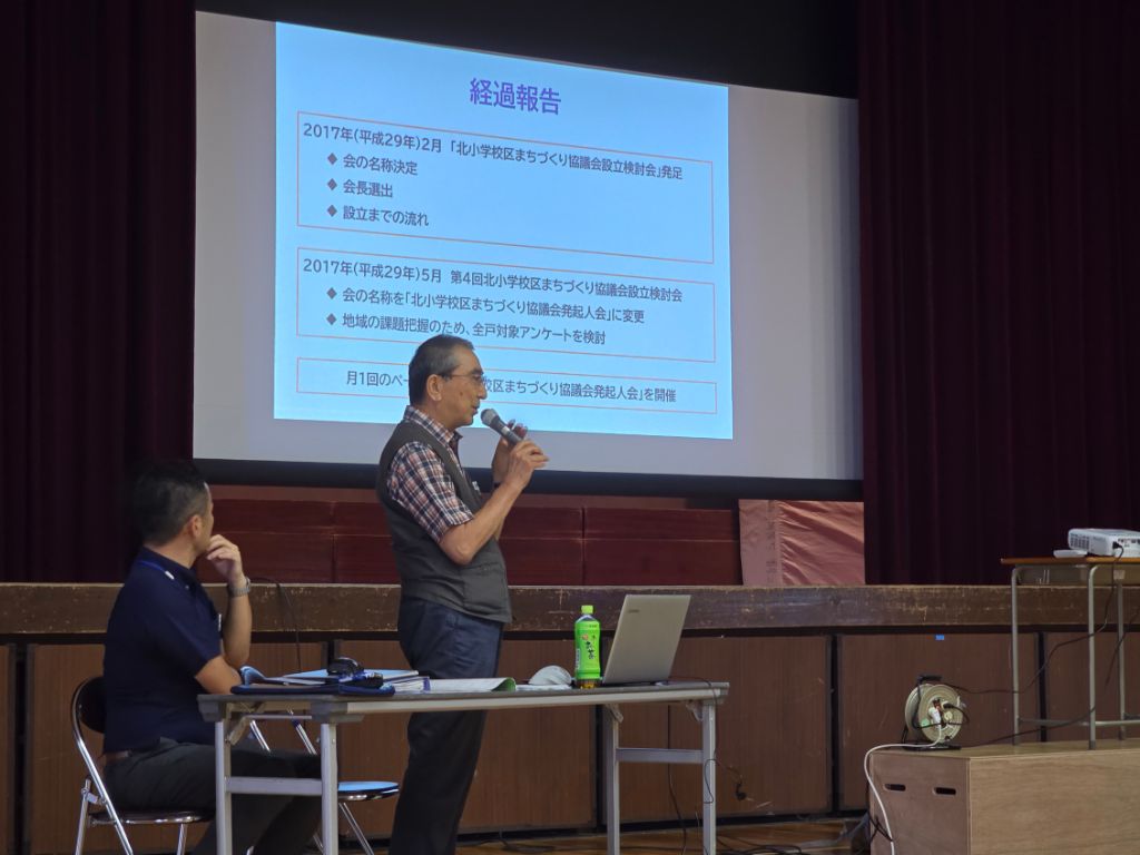 体育館にテーブルが設置され、グループに分かれてお茶を飲みながら、楽しそうに話し合いをしている様子の写真