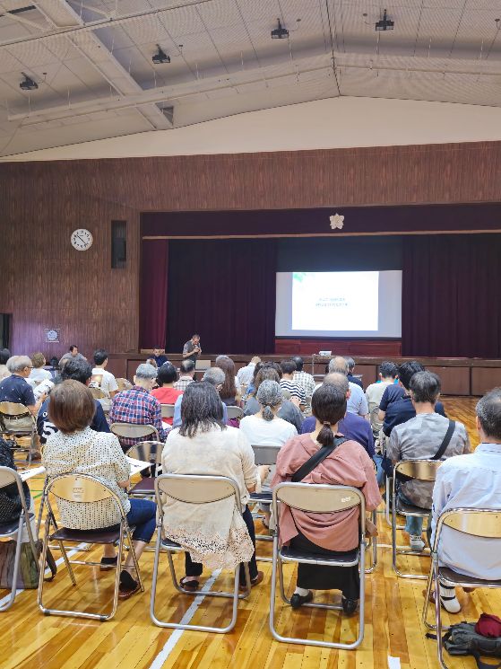 北小学校区まちづくり協議会の参加者集まって、ガッツポースをして笑顔で写っている集合写真