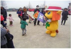 学校のグラウンドで消防士のゆるキャラとまるばつゲームをする参加者親子たちの写真