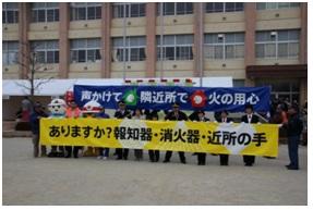 校舎の前で標語川柳の書かれた2つの横断幕を持って記念撮影している写真