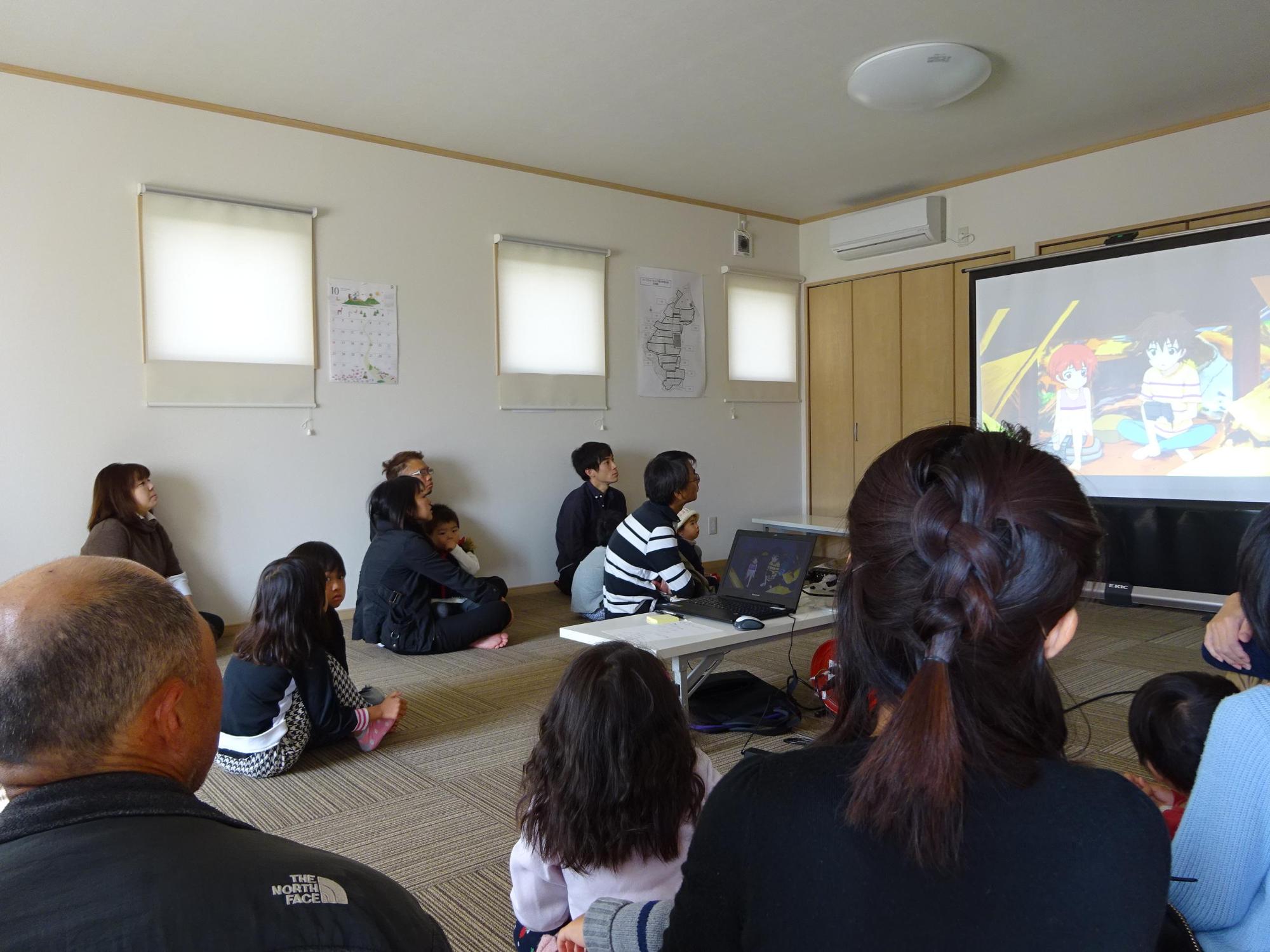 室内スクリーンのDVD上映を見ている参加者親子たちの写真