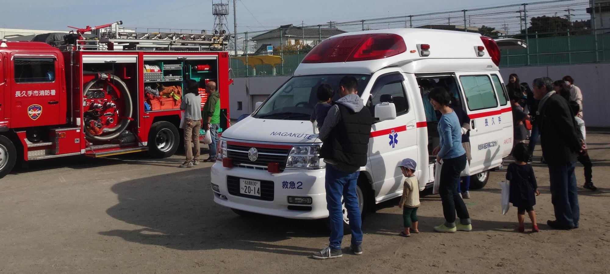 消防車両と救急車両の中を見学する人々の写真