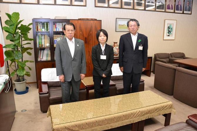 市長と濃紺のスーツを着た関係者の男性と黒色のスーツを着た女性が並んで写っている写真