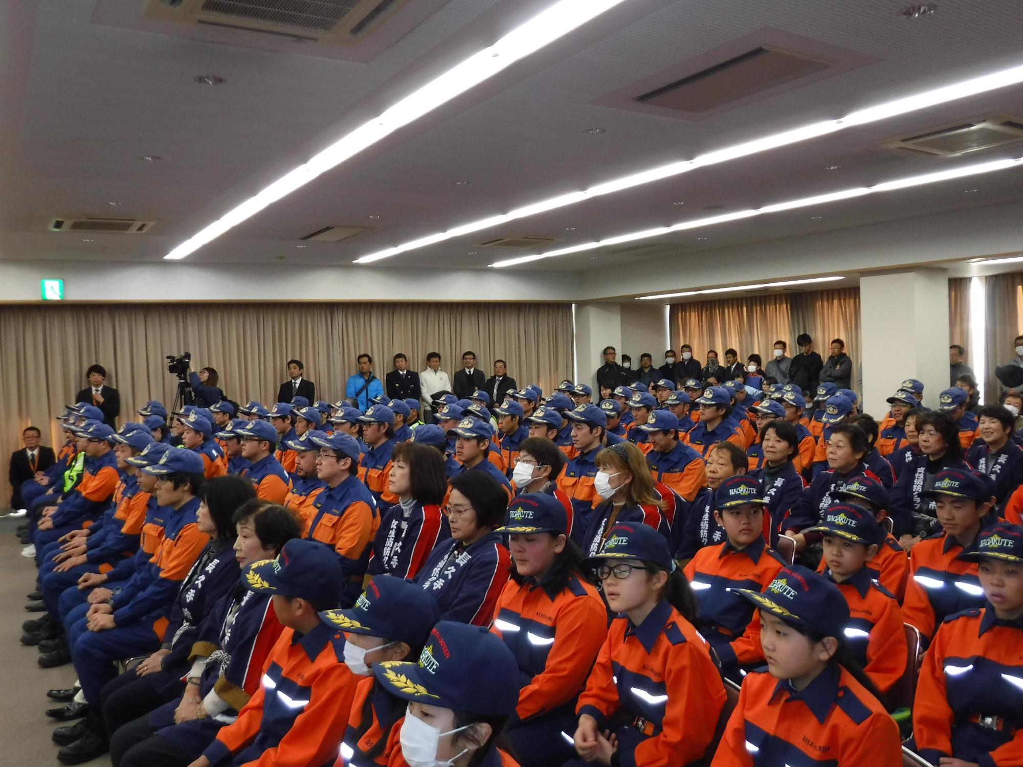 長久手市キッズ消防団、長久手市消防団及び女性消防クラブ、応急救護ボランティアの関係団体の方たちが椅子に並んで座っている写真