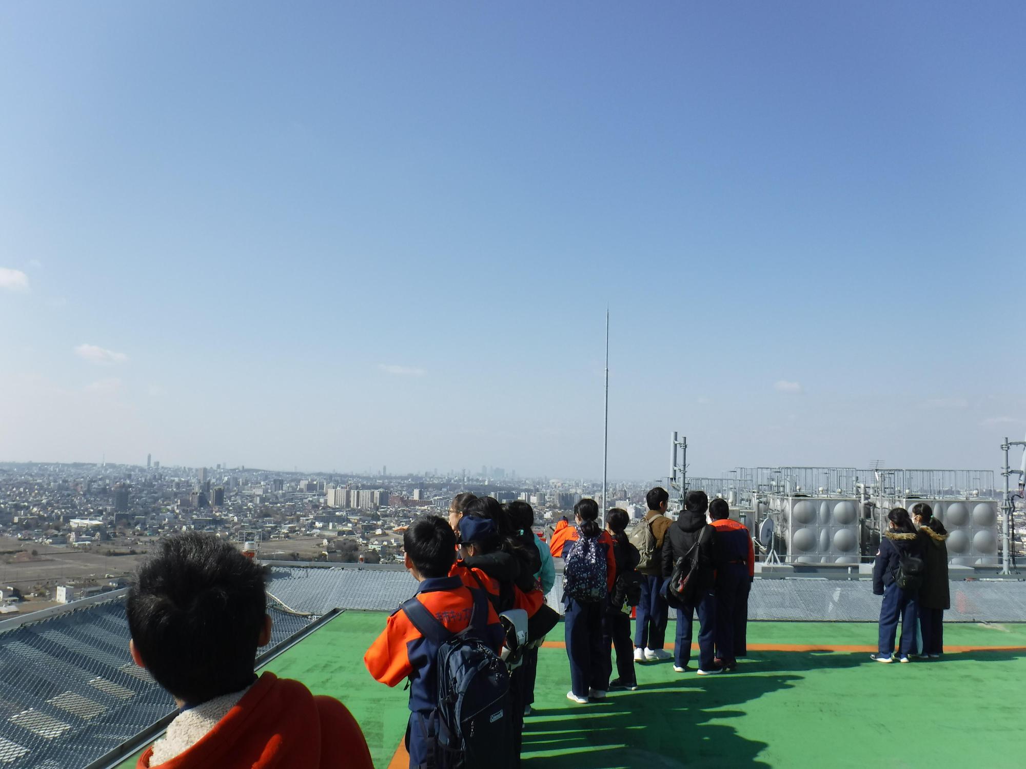 屋上ヘリポートの周りから辺りを見渡している長久手市キッズ消防団の写真