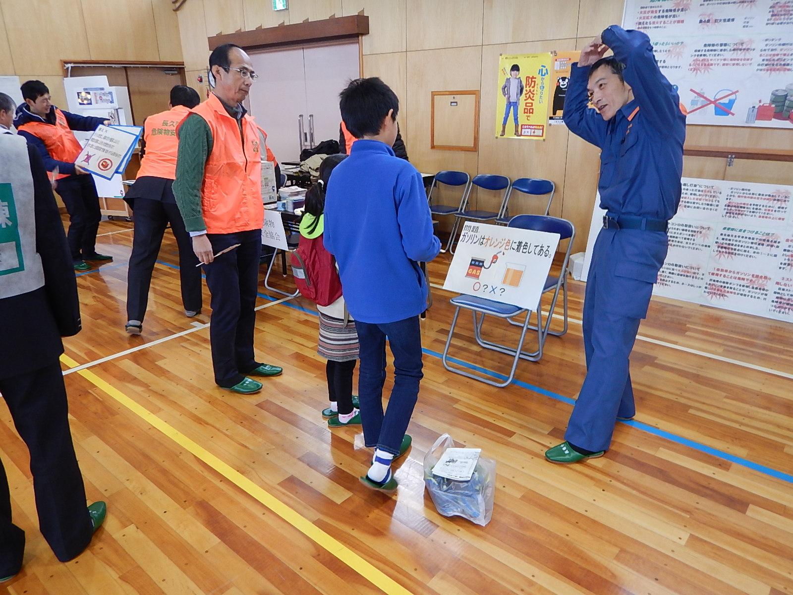 体育館内にパネルが展示されている長久手市危険物安全協会のブースで参加者の子供たちに説明するスタッフの写真