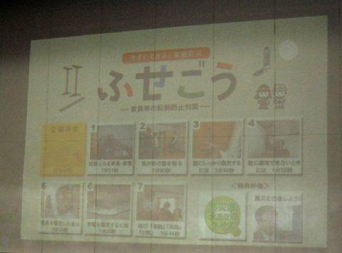 スクリーンに映し出された、家具転倒防止啓発のDVDを上映している様子の写真