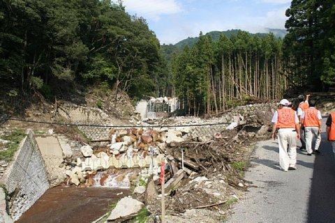 堤防が壊れ泥水が流れている災害現場を視察する長久手市自治会連合会長と区長会の代表者4名の写真