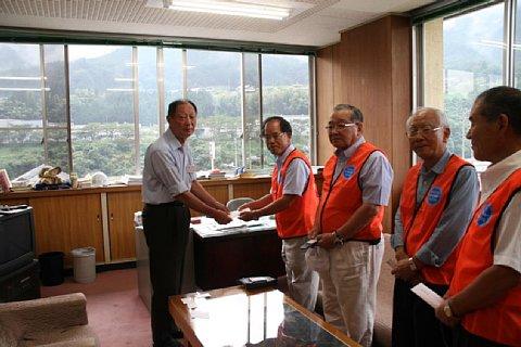 長久手市自治会連合会長と区長会の代表者4名の内一番左にいる眼鏡をかけた男性が義援金を南木曽町長へ手渡す写真