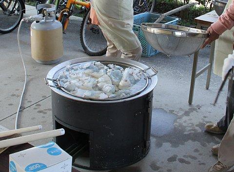 大きな釜の中に、湯がいたたくさんの袋が入っている様子の写真