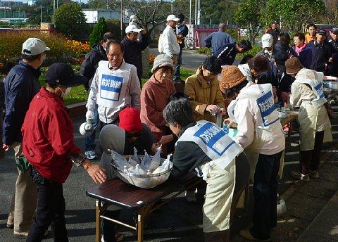 避難訓練会場の外側に長机を設置し、炊き出し訓練を行っている様子を参加者が見ている写真