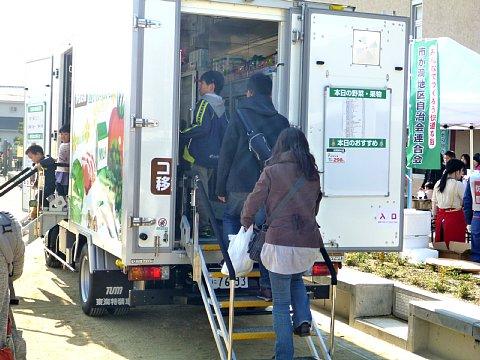 生活協同組合コープあいちが持って来た、後ろを開けた災害時移動販売車に参加者が階段を上がって見学している写真