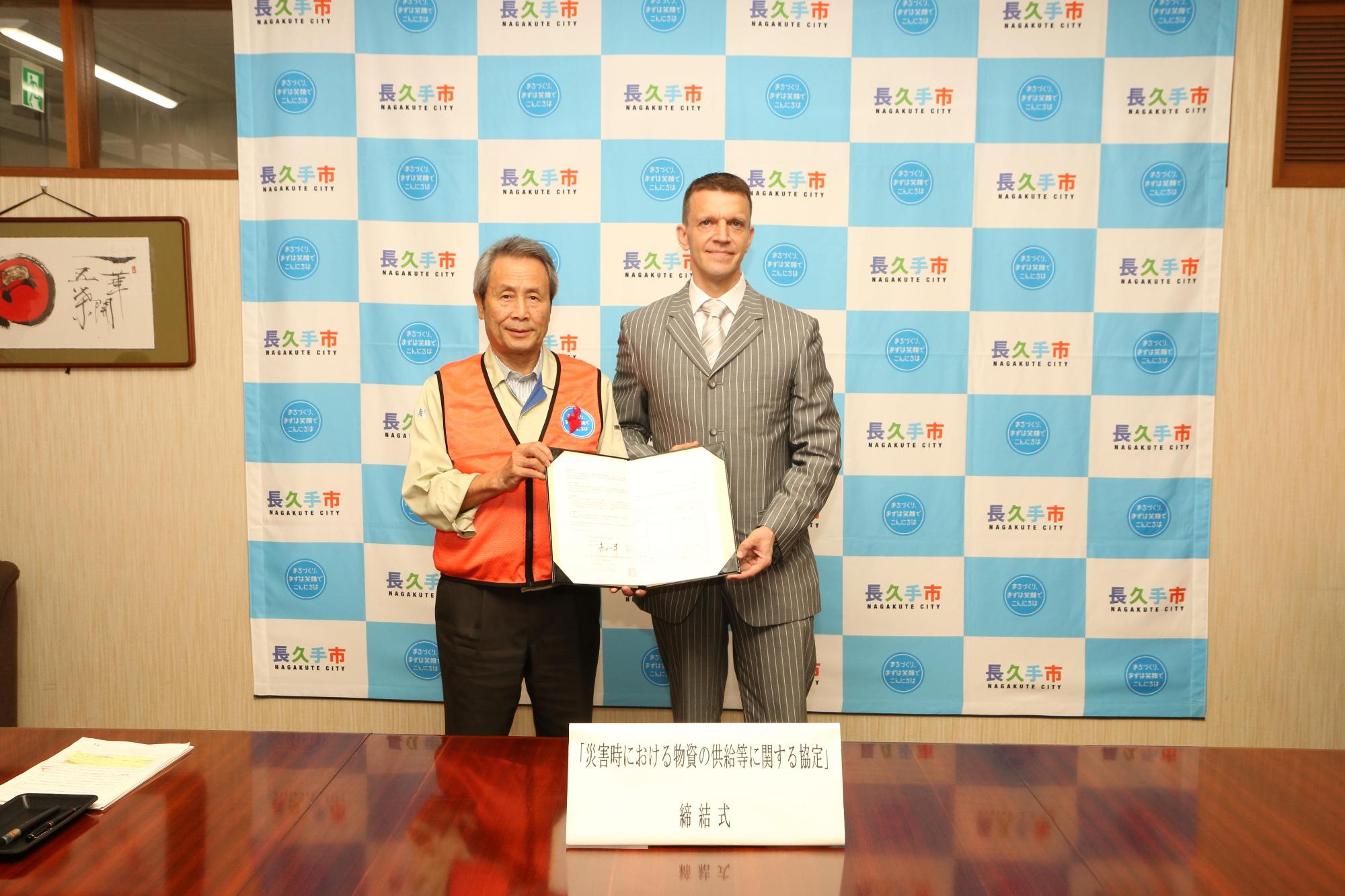 関係者2人が一緒に協定書を持ち記念撮影をしている写真
