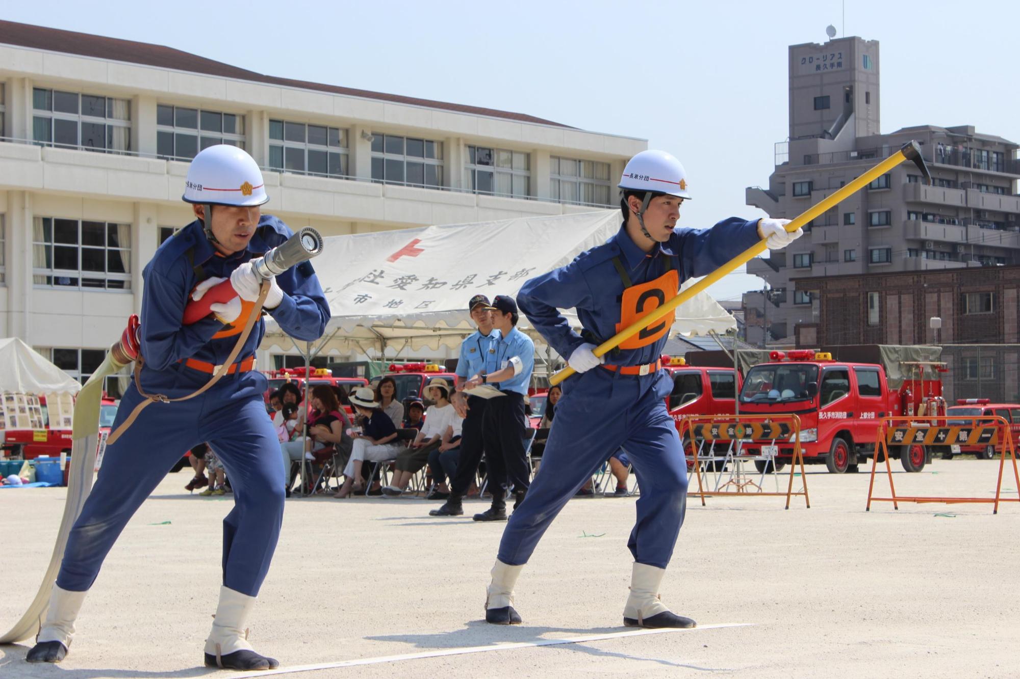 消防操法大会にて放水ホースを持つ消防団員と、かぎの付いた棒を持つ消防団員の写真