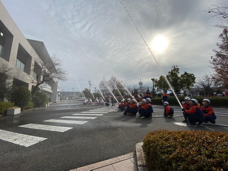 消防団員が建物に向かって放水作業を行っている写真