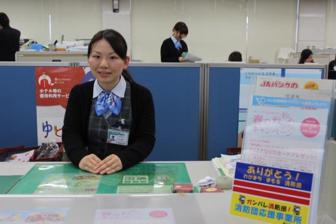 あいち尾東農協 長久手支店の窓口に女性職員が座っており、カウンターに消防団応援事業所表示証が掲出してある写真