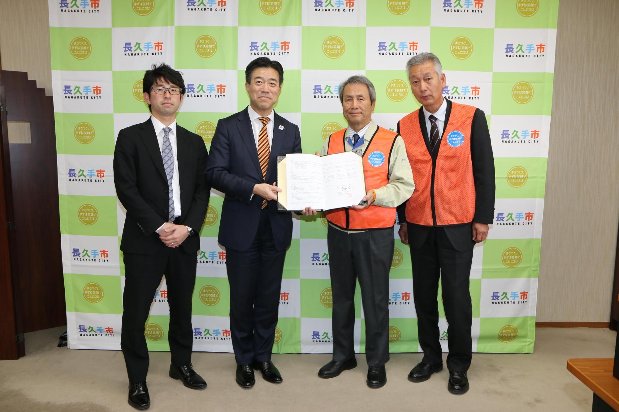 市長とスーツを着た男性が一緒に協定書を持っており、その両隣に男性2名が写っている写真