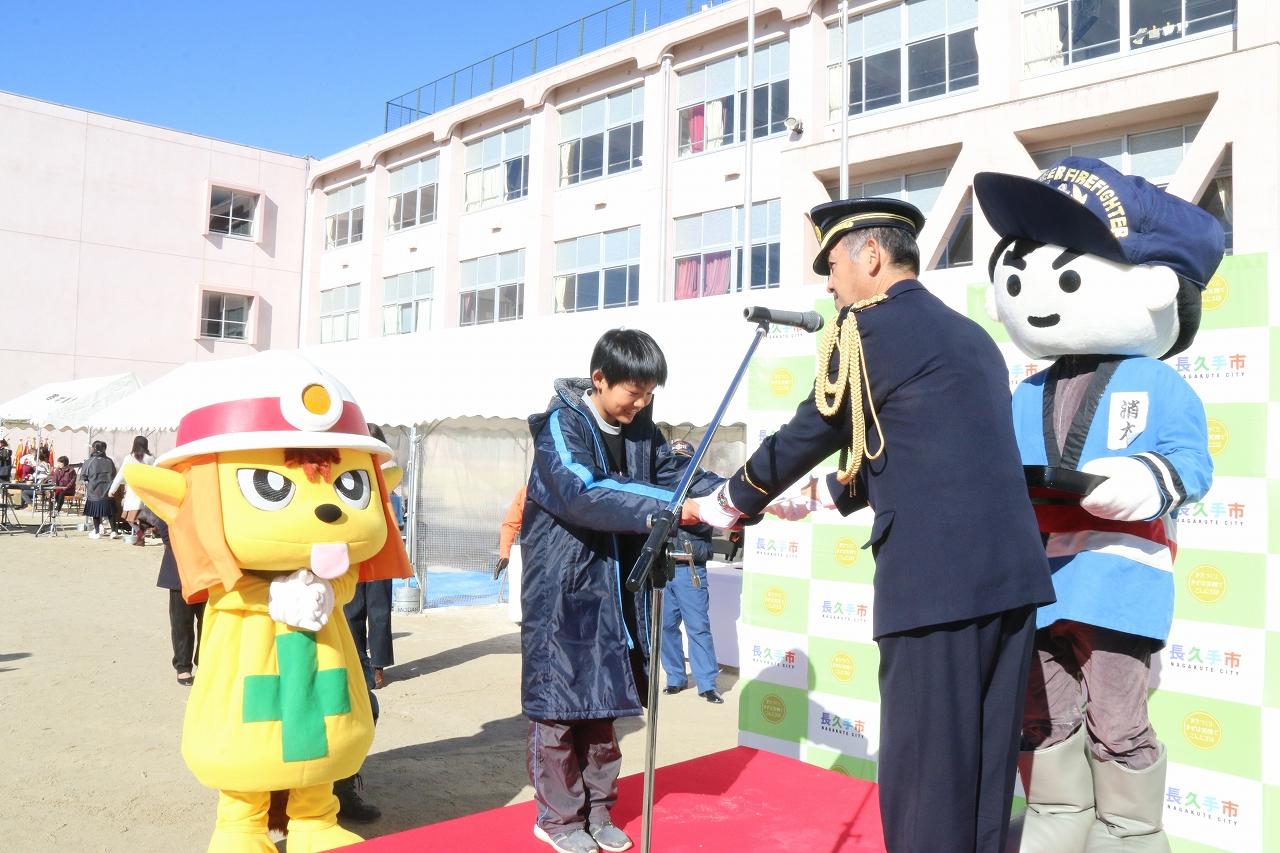 ゆるキャラの前で表彰される学生の写真