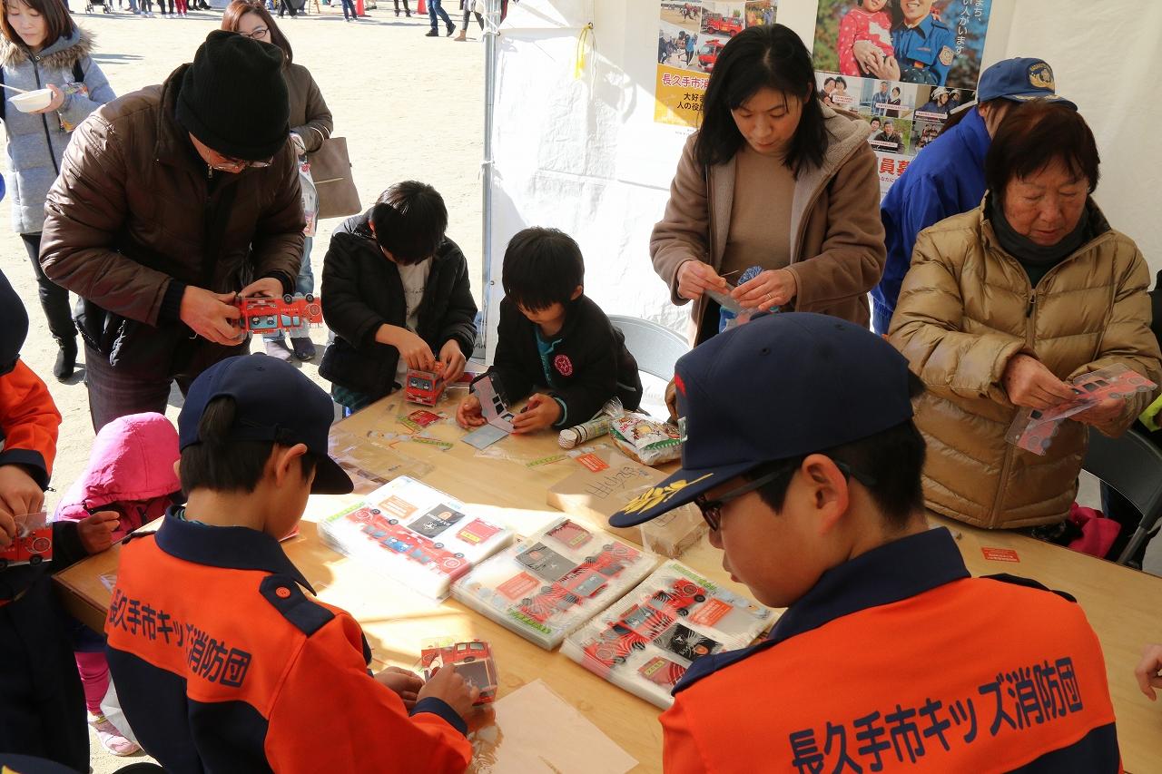 キッズ消防団員や参加者親子たちが消防車の模型をテントの中で組み立てている写真