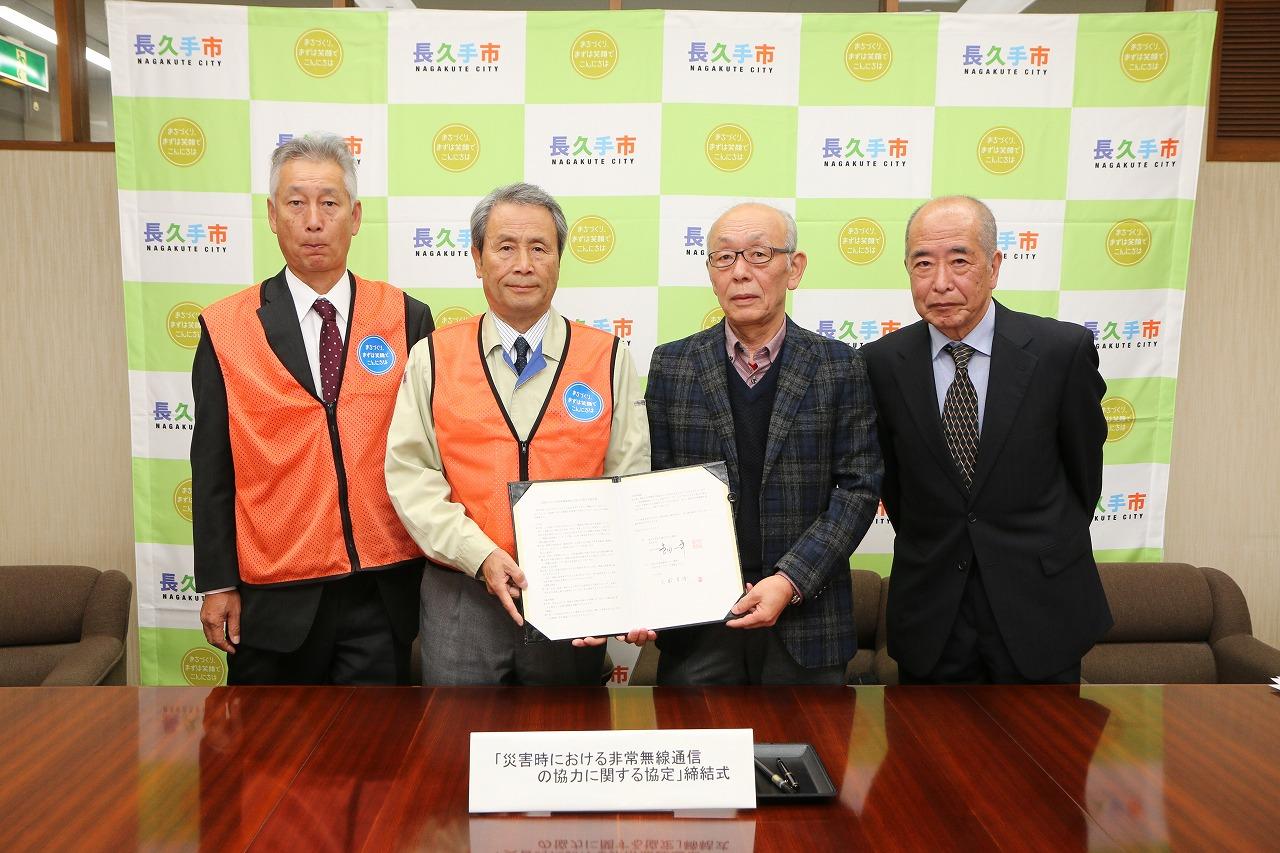 協定書を手に4人の男性が記念撮影している写真