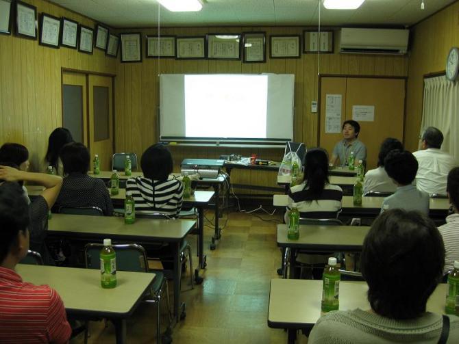 前方のホワイトボードの横で話をしている安心安全課職員と着席して話を聞いている受講者の写真