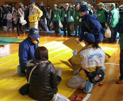 脚を伸ばして座っている女性の周りに、応急救護ボランティアの女性と2名の女性消防団員が囲んで応急手当の訓練をしている写真