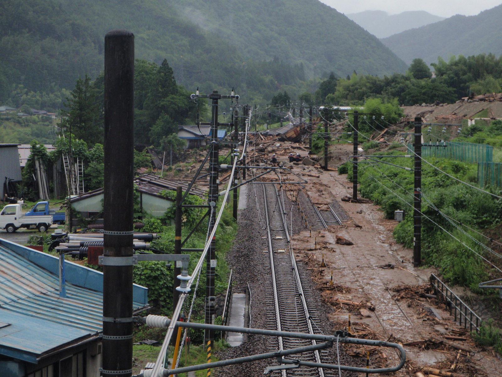 高台から撮影された土砂や岩で覆われている線路の写真