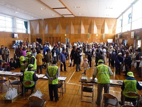 体育館内の手前に受付を設置している奥に、避難訓練に参加している大勢の参加者が密集している写真