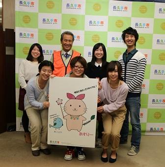 あすりーのイラストのを真ん中にして感謝状をもち笑顔で記念写真をしている関係者の人達の写真