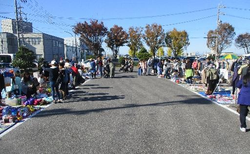 道路の両脇にリサイクルマーケットの店舗が並んでおり、お客様がみている写真