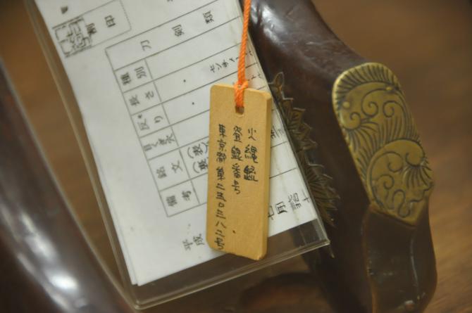 火縄銃に紐で木の札が付いており、札に火縄銃の番号が記載されてある写真