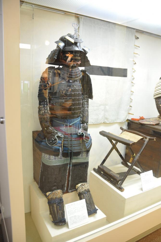 ガラスケースの中に展示されてある切付紺絲威二枚胴具足・鉄黒塗十六間筋兜(明珍)の写真