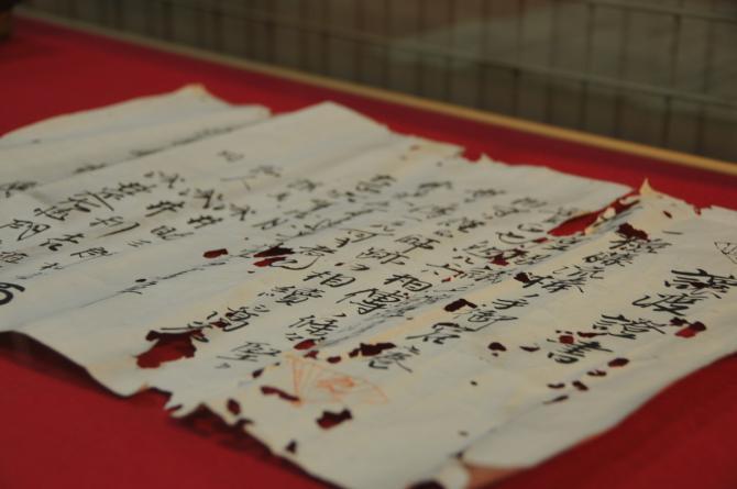 所々に穴が開いてある譲渡證書が広げられて置かれてある写真