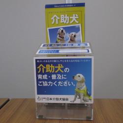 介助犬の育成・普及にご協力ください。と書かれた文字の横に介助犬の写真が載っている募金箱の写真