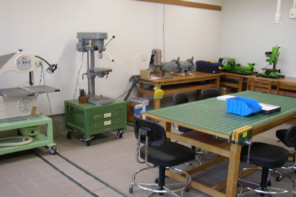 中央に作業台があり、壁の周りに色々な機械が置かれている工房室の写真