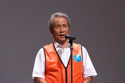 オレンジ色のベストを着て挨拶をしている市長の写真