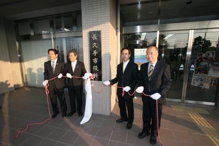 中央に「長久手市役所」と書かれた銘板、その両脇に立っている市長と3名の来賓の方々の写真