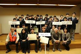 舞台の上に選手の皆さんがチームのプラカードを持って集合しており、市長と関係者の方々と一緒に写っている集合写真