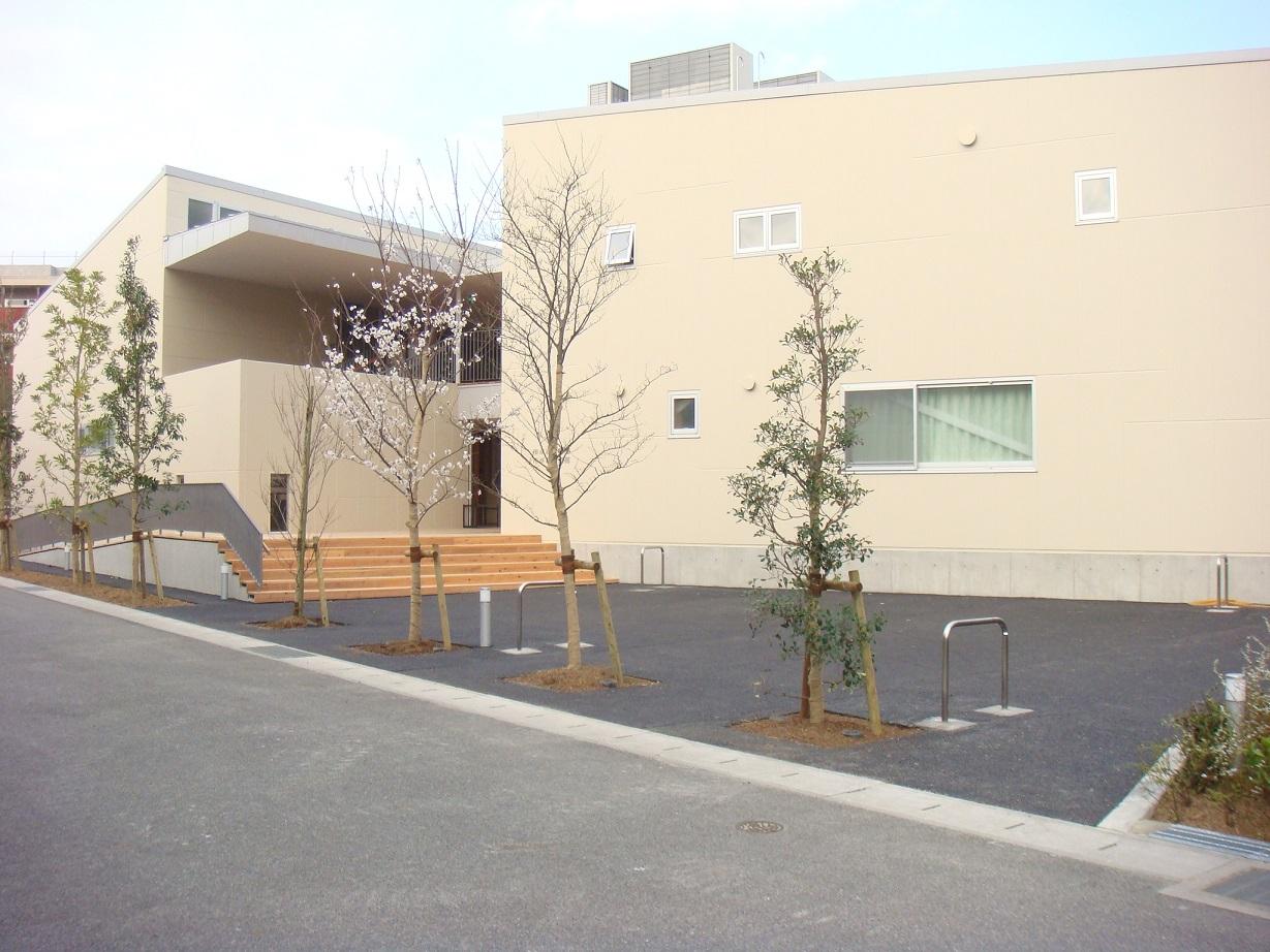 園舎の横に数本の木が植えてあり外壁がベージュ色をした市が洞保育園外観写真