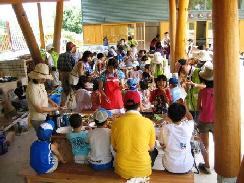 沢山の人々が机に座って食事やお喋りをしている写真