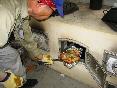 男性がオーブン釜の中の食材を見ている写真